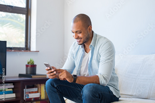 African man typing phone message