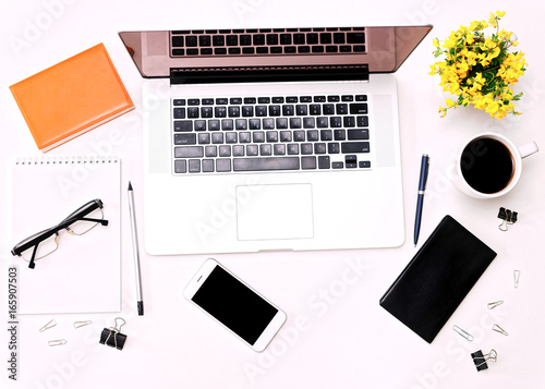 Workspace with laptop keyboard mobile phone coffee glasses and flowers