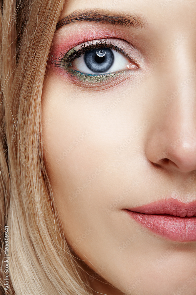 Female half face with pink and green blue eyes makeup Female half face with pink and green blue eyes makeup