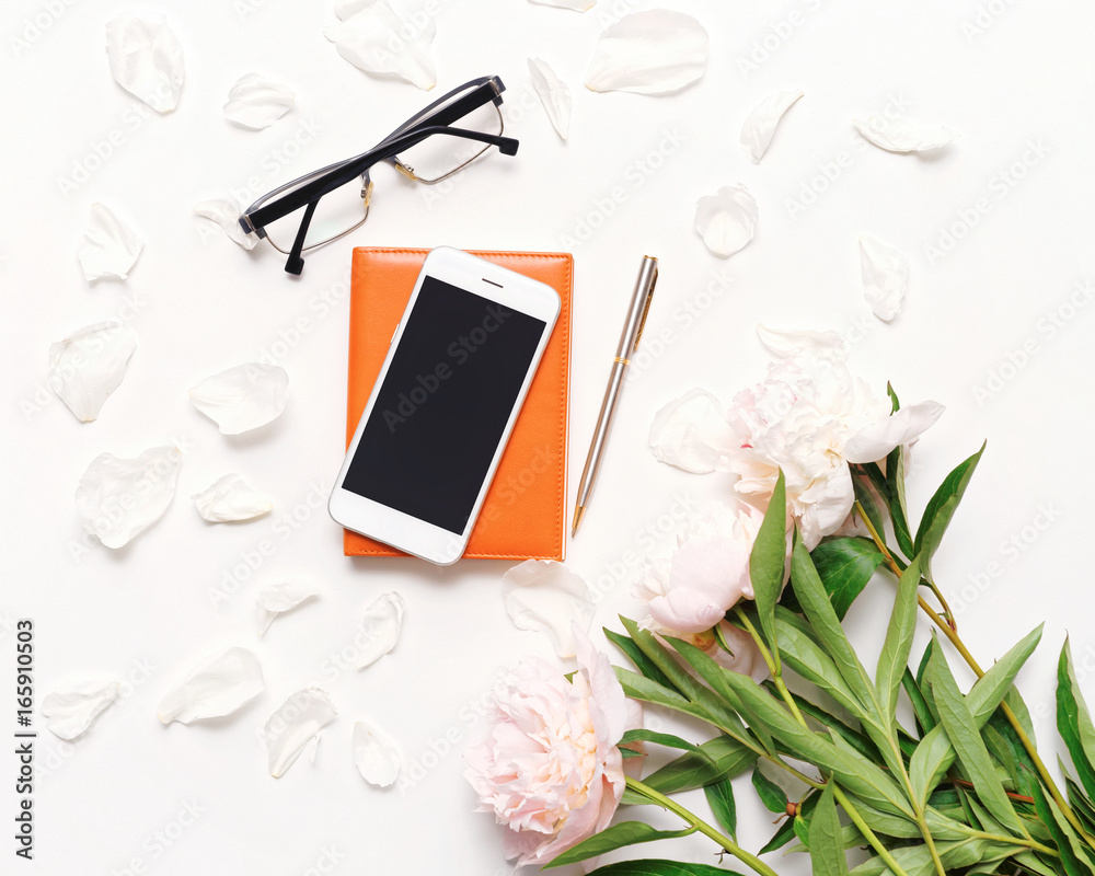 Workplace with mobile phone notebook pen glasses peony flowers Workplace with mobile phone notebook pen glasses peony flowers