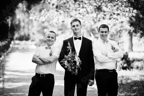 Handsome groom walking with his bestmen or groomsmen in the park on a wedding day. Black and white photo. photo