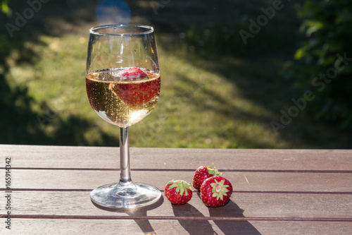 Backlit glass with sparkling wine and strawberries