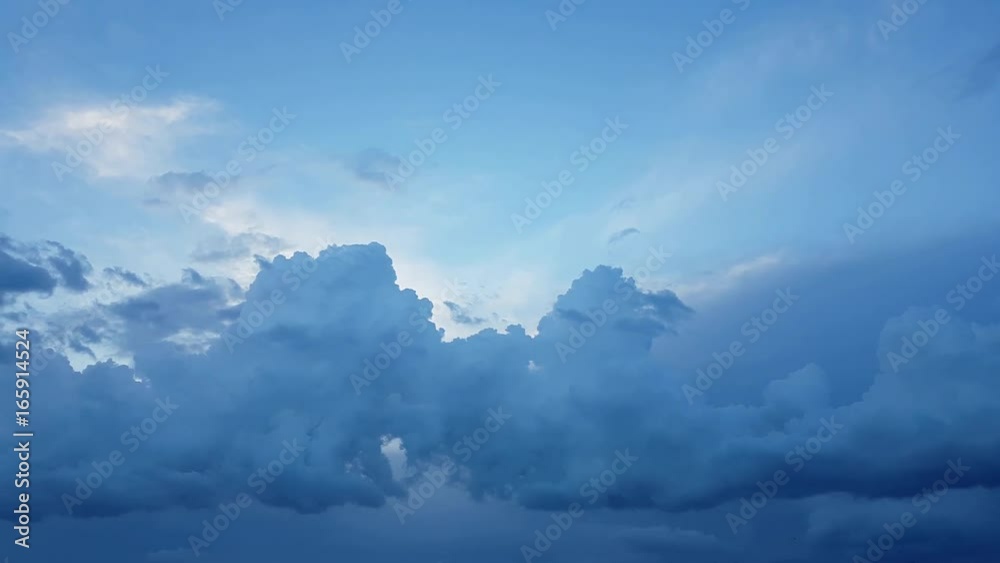 Blue sky with gray and black clouds. Birds flying over cloudy sky. The Sun between clouds.