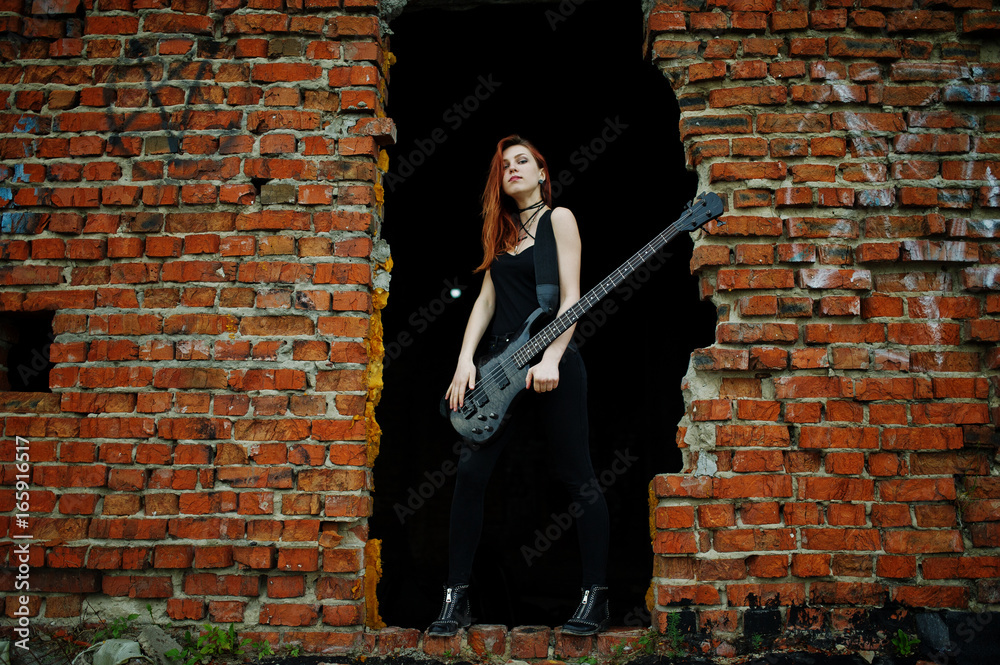 Φωτογραφία Red haired punk girl wear on black with bass guitar at abadoned place