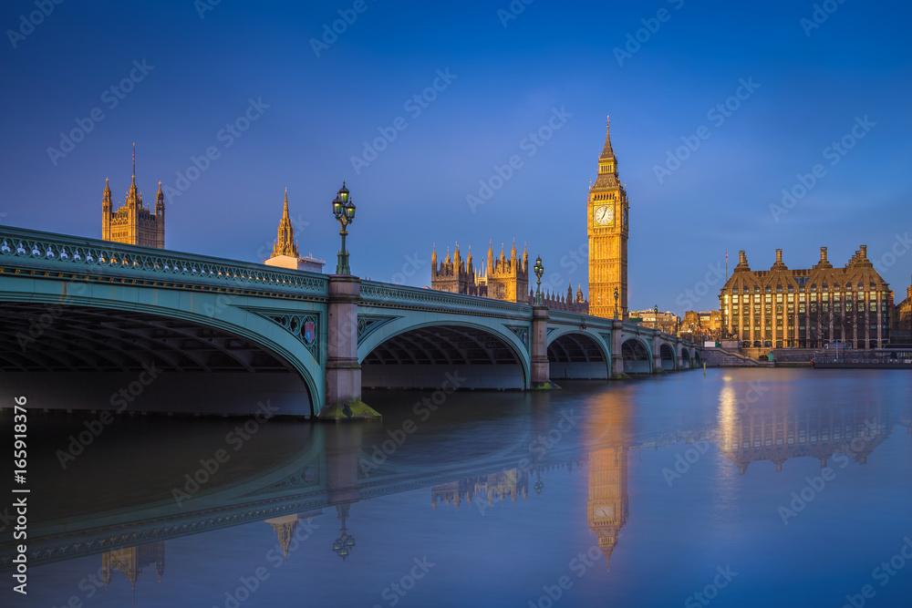 London, England - The iconic Westminster bridge and Big Ben reflecting on River Thames at sunrise with clear blue sky