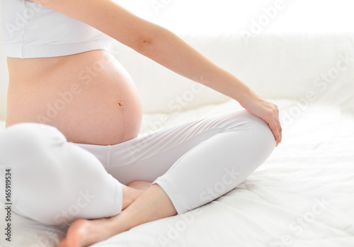 Pre-natal exercises. Beautiful pregnant woman exercising while sitting in lotus position