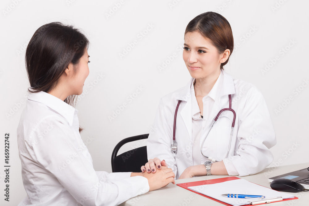 Hand of doctor reassuring her female patient in the consulting room.