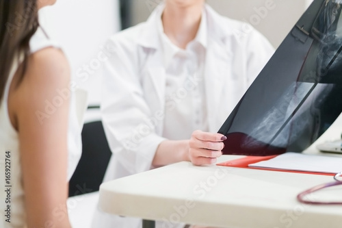  Female doctor holding  the Mammogram film image and give advice her patient in consulting room.