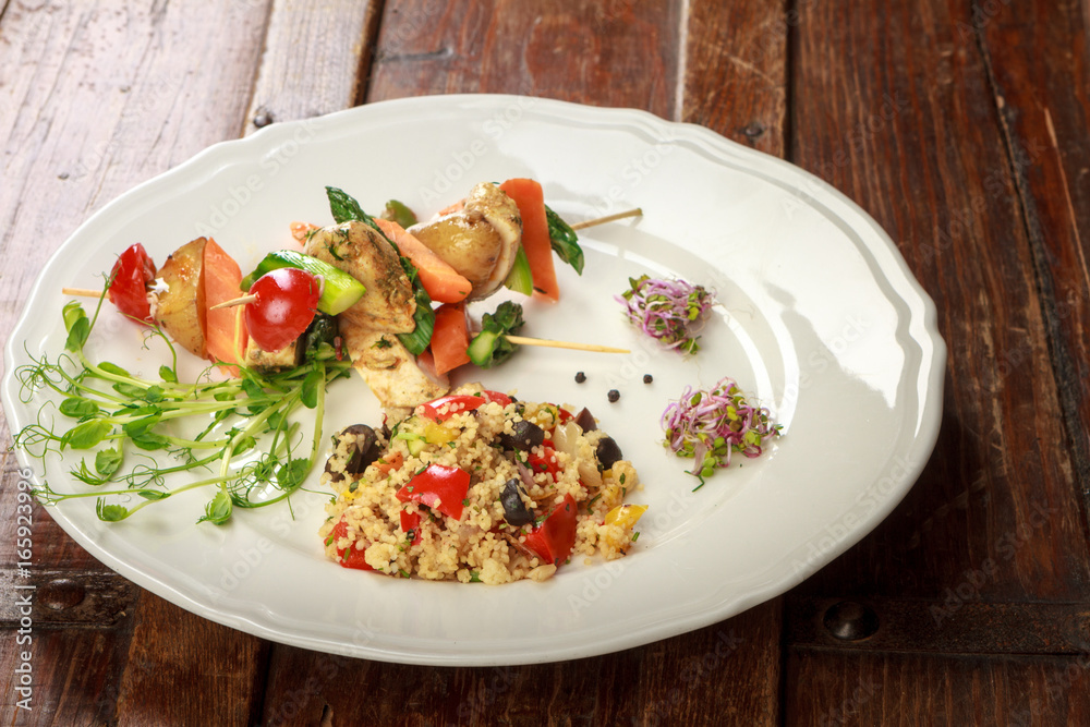 White plate with meal composed of healthy skewers and rice.