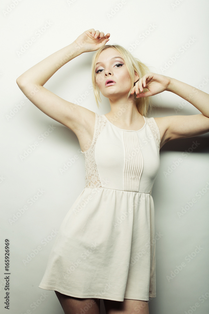 Naklejka premium fashion blond woman in white dress posing in studio