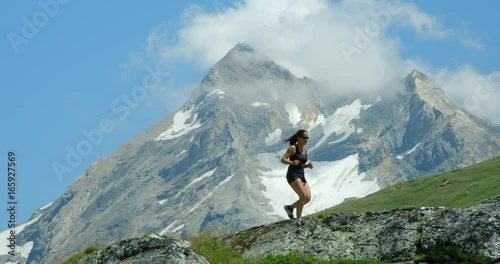 A woman running in a high mountain range  with summits and glaciers photo