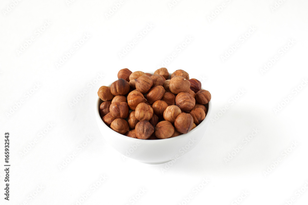 Purified hazelnuts in a bowl on a white background Purified hazelnuts in a bowl on a white background