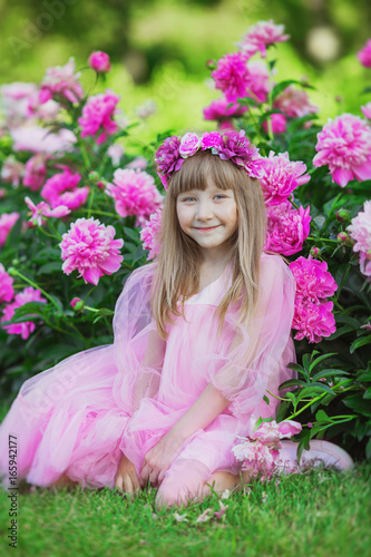 Portrait of smiling little girl near peonies