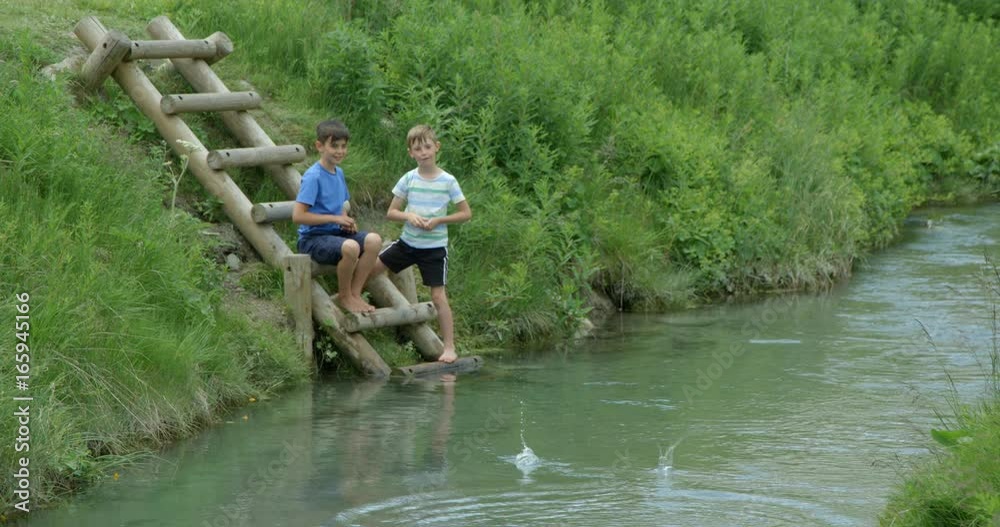 Two young boys throwing stones into a pond in slow motion. Two young boys throwing stones into a pond in slow motion.