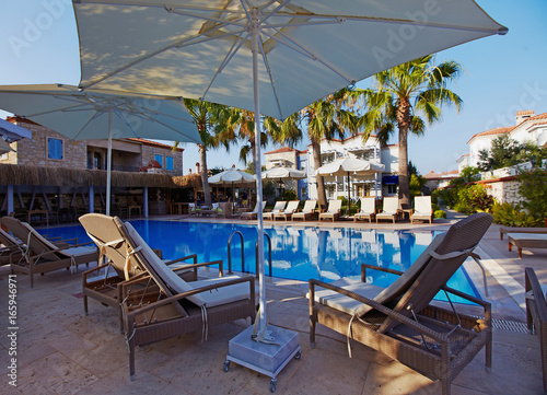 View of relaxing pool in small boutique hotel with palms and garden