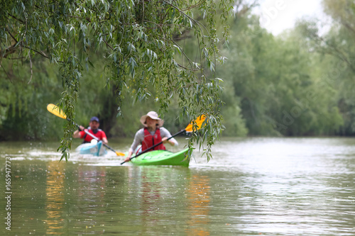 Wallpaper Mural Man and girl in blue and green kayaks in spring Danube river. Kayaking in nature reserve of Danube Delta Torontodigital.ca