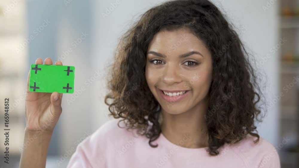 Mixed race woman holding card in green color, smiling, healthcare, advertisement Mixed race woman holding card in green color, smiling, healthcare, advertisement