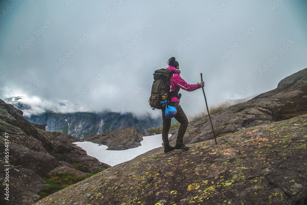 Girl stands on the peak of sandstone rock . Beautiful moment the miracle of nature. Morning mountain background. Girl watch foggy miracle. Trolltunga hiking route
