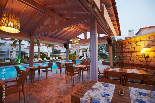Evening view of cozy small Mediterranean boutique hotel pool with chaise-longue, relaxing
