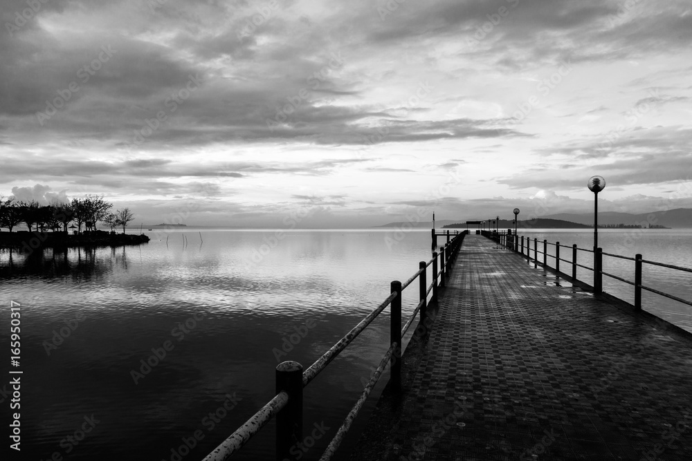 Fototapeta premium A first person view of a pier under a beautiful sky at sunset, reflecting on water
