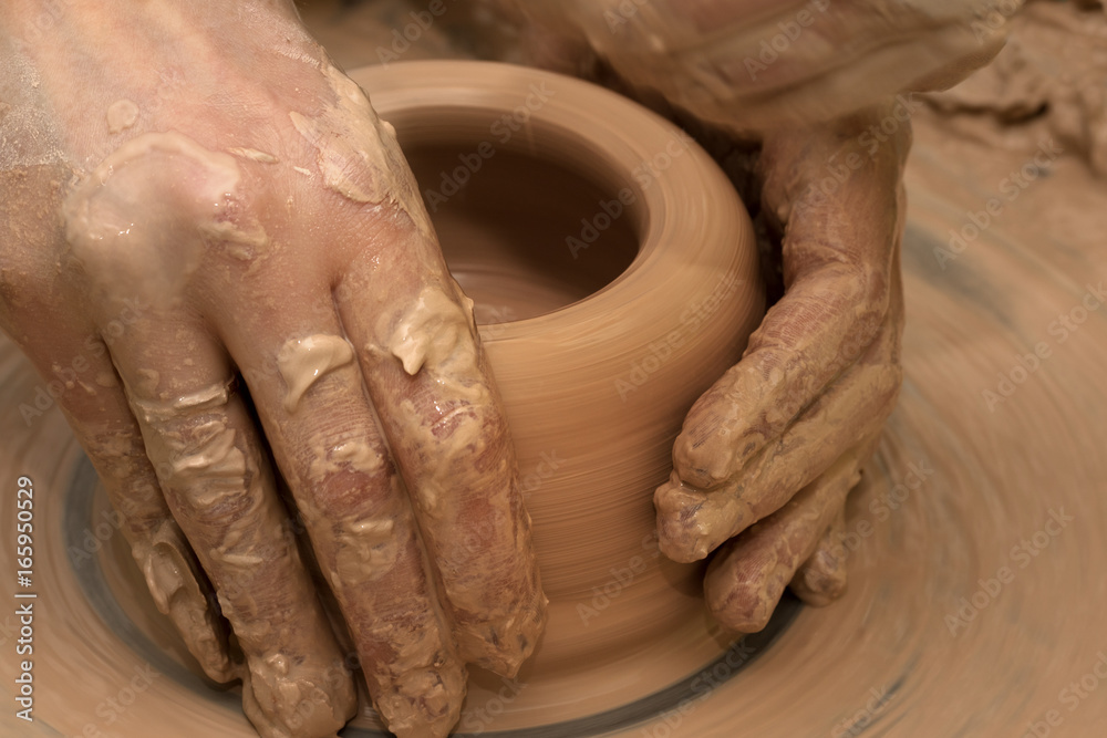 Women hands in process of making clay bowl on pottery wheel