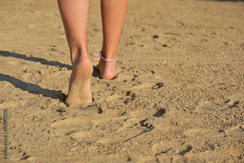 girl's legs walking on a sandy beach