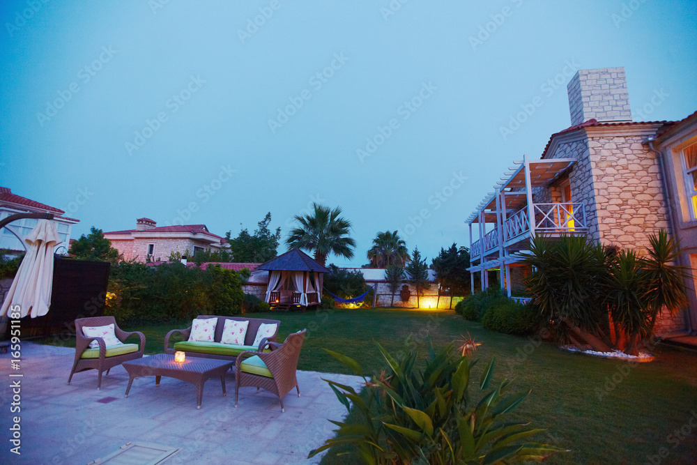 Fototapeta premium Evening view of cozy small Mediterranean boutique hotel pool with chaise-longue, relaxing