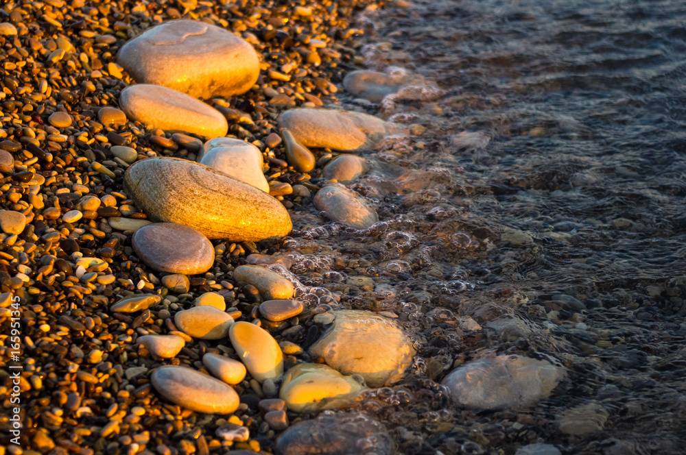 sea pebble beach with multicoloured stones, waves with foam sea pebble beach with multicoloured stones, waves with foam