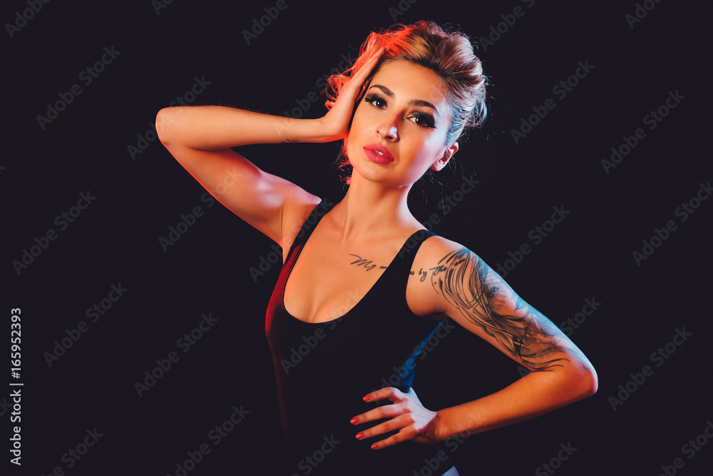 Beautiful female model posing at studio in the light flashes
