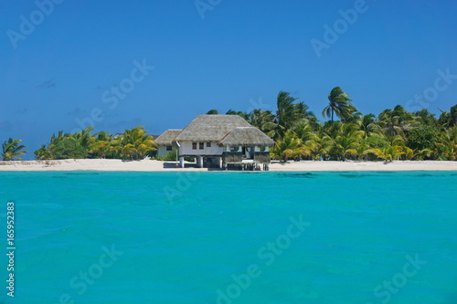 Coastline with a tropical beach house and the turquoise water of the inner lagoon of the atoll of Tikehau, Tuamotus archipelago, French Polynesia, south Pacific ocean