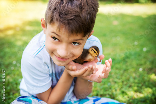 Young adorable boy holding cute duckling outdoors