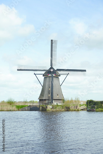 Dutch windmill in the afternoon build and standing next to polder water in kinderdijk south holland used to drain water out by using wind power and keep land dry.