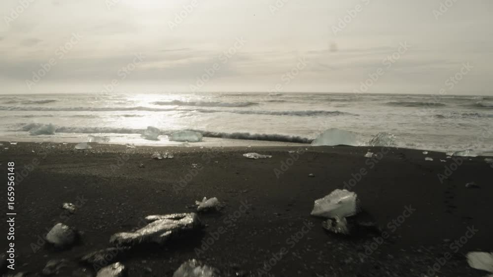 Slow motion aerial, waves break on icy beach Slow motion aerial, waves break on icy beach