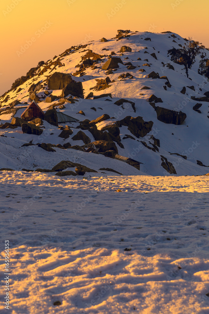 First rays of sun falling on a snow mountain called Triund in Mcleodganj,Dharamshala, Himachal pradesh, India at golden hour.