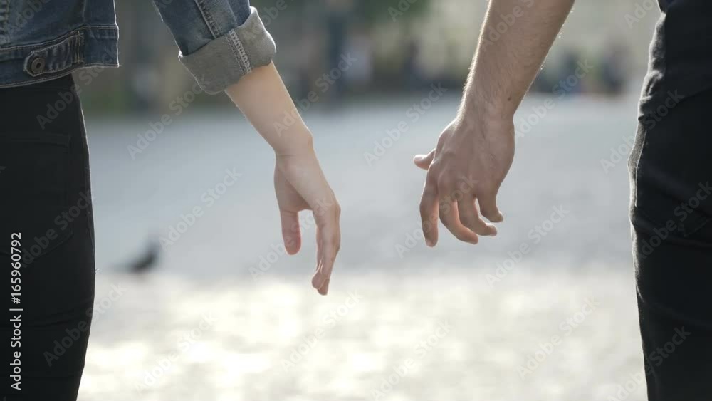 Closeup of man and woman touching hands and enjoying a walk together in a park