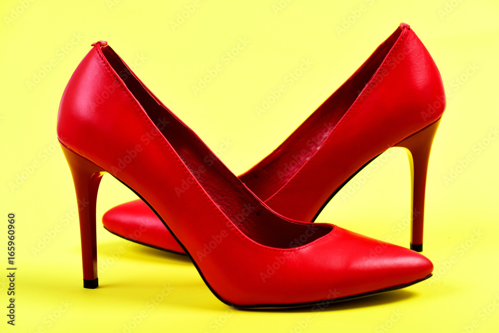 Fancy female shoes in red color on yellow background Fancy female shoes in red color on yellow background