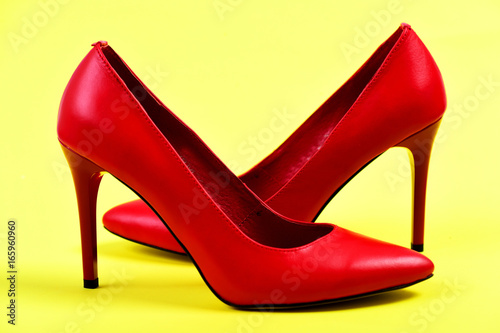 Fancy female shoes in red color on yellow background