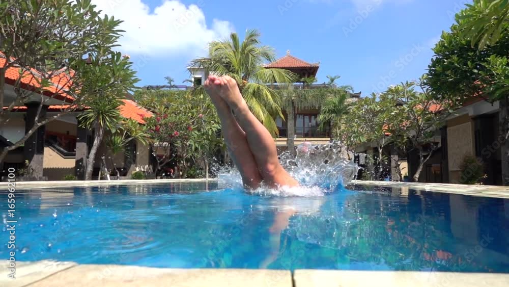 SLOW MOTION CLOSE UP: Young woman on summer vacation jumping head first into blue pool water for refreshment on hot sunny day. Girl in pink bikini diving into clear pool water in empty luxury resort