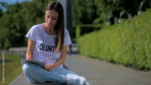 Concentrated female volunteer making notes outdoors photo