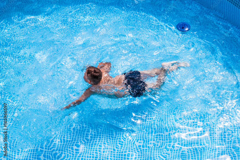 Young boy kid child eight years old splashing in swimming pool having fun