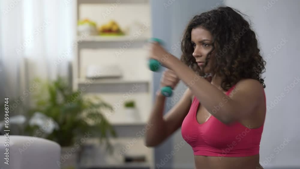 Sporty girl doing boxing movements with dumbbells in hands, workout, fitness Sporty girl doing boxing movements with dumbbells in hands, workout, fitness