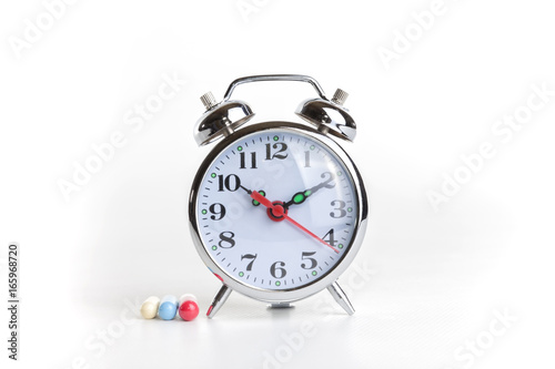 Medicines and alarm clock on white background.