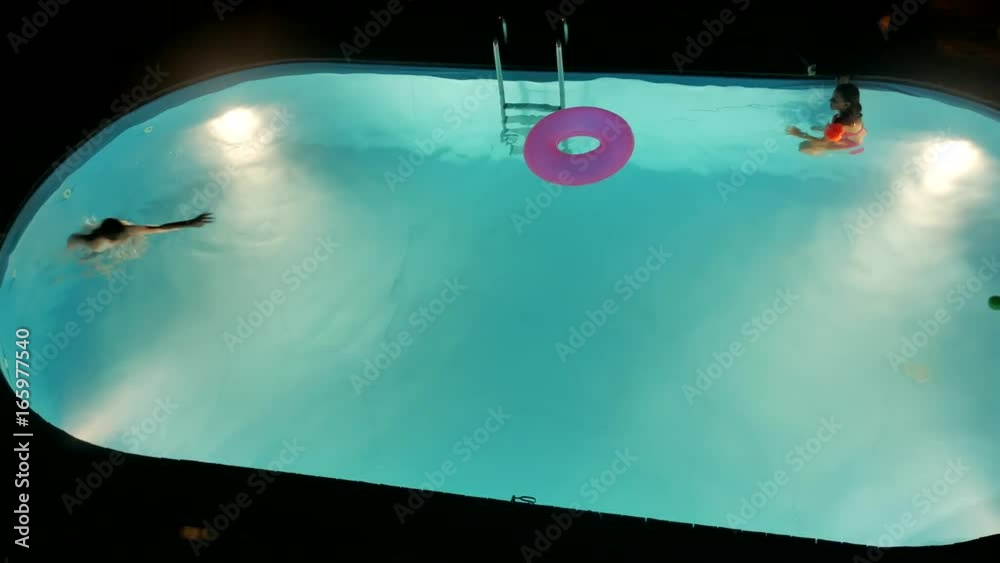 Boy and girl bathe in the pool at night. Children kids amusement swim in the water Boy and girl bathe in the pool at night. Children kids amusement swim in the water