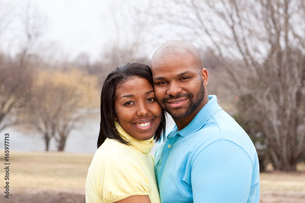 Happy African American couple hugging outside.