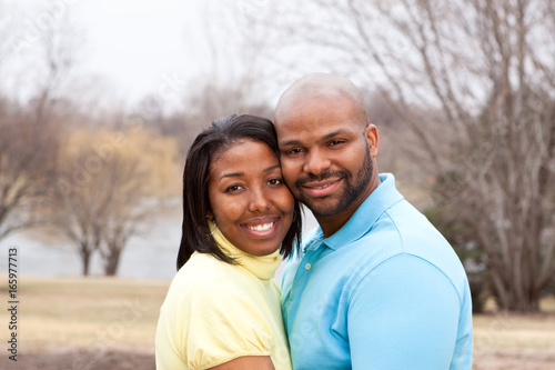 Happy African American couple hugging outside.