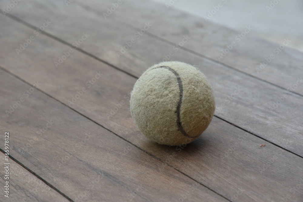 Old tennis ball on wooden floor