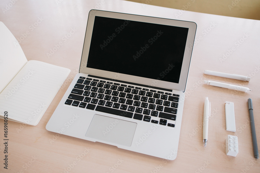 Laptop and white stationery on a light wood table. Laptop and white stationery on a light wood table.