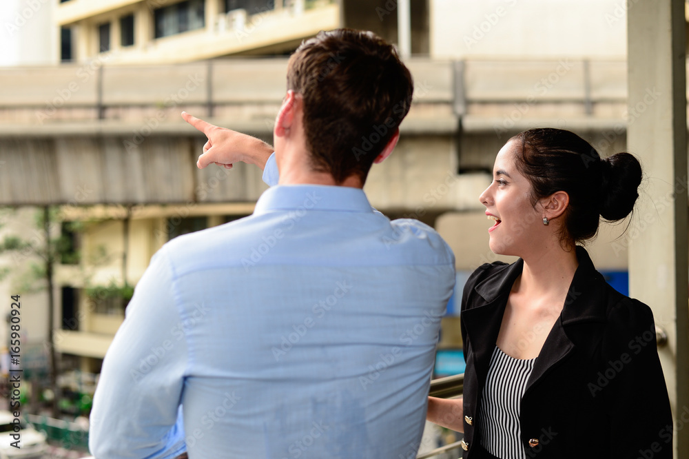 businessman and businesswoman talk about business outdoor, he Point the finger at some where and woman smile businessman and businesswoman talk about business outdoor, he Point the finger at some where and woman smile