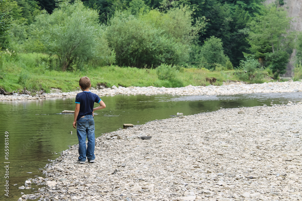 Boy near mountain river in Carpathians, Ukraine Boy near mountain river in Carpathians, Ukraine