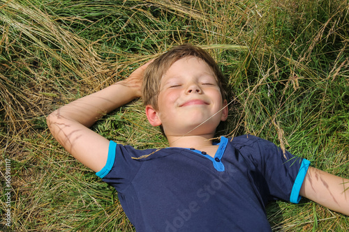 Handsome boy lying on meadow grass